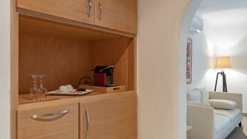 A compact room with a wooden wardrobe, a small table with a lamp, and a white sofa.