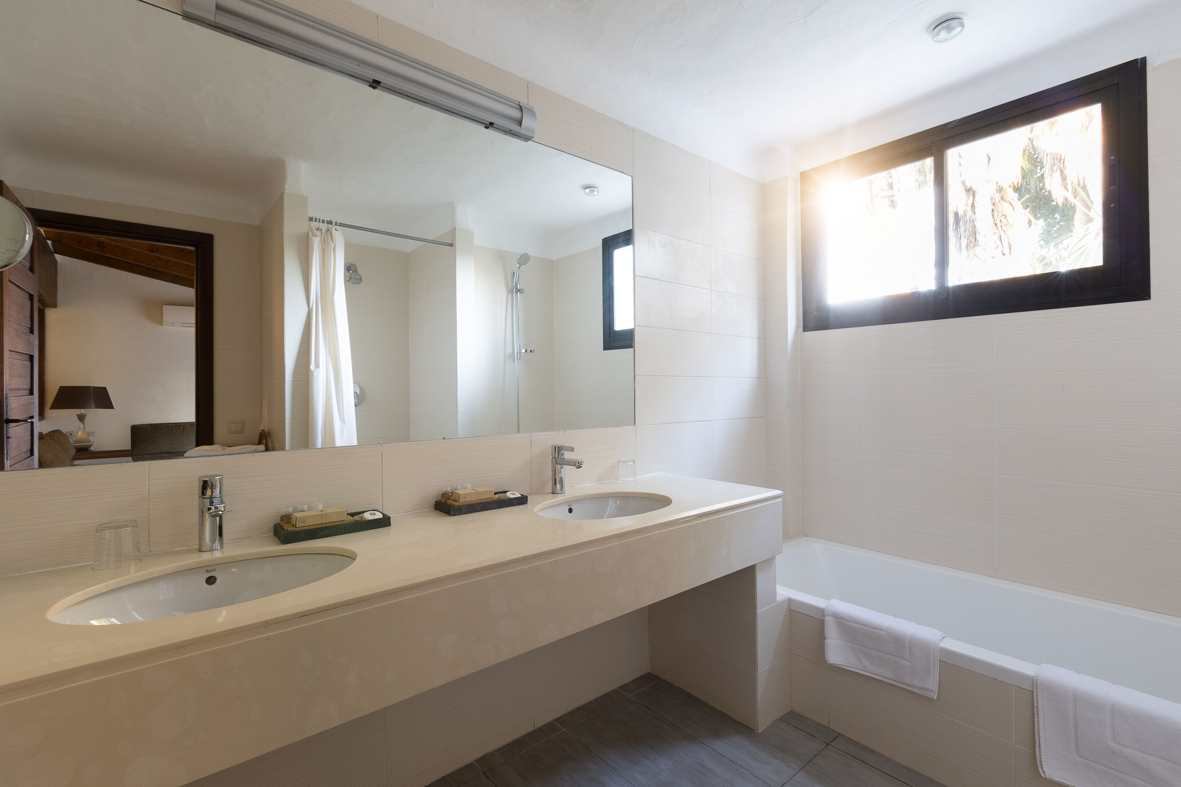 A modern bathroom with two sinks, a large mirror, a shower, and a bathtub.