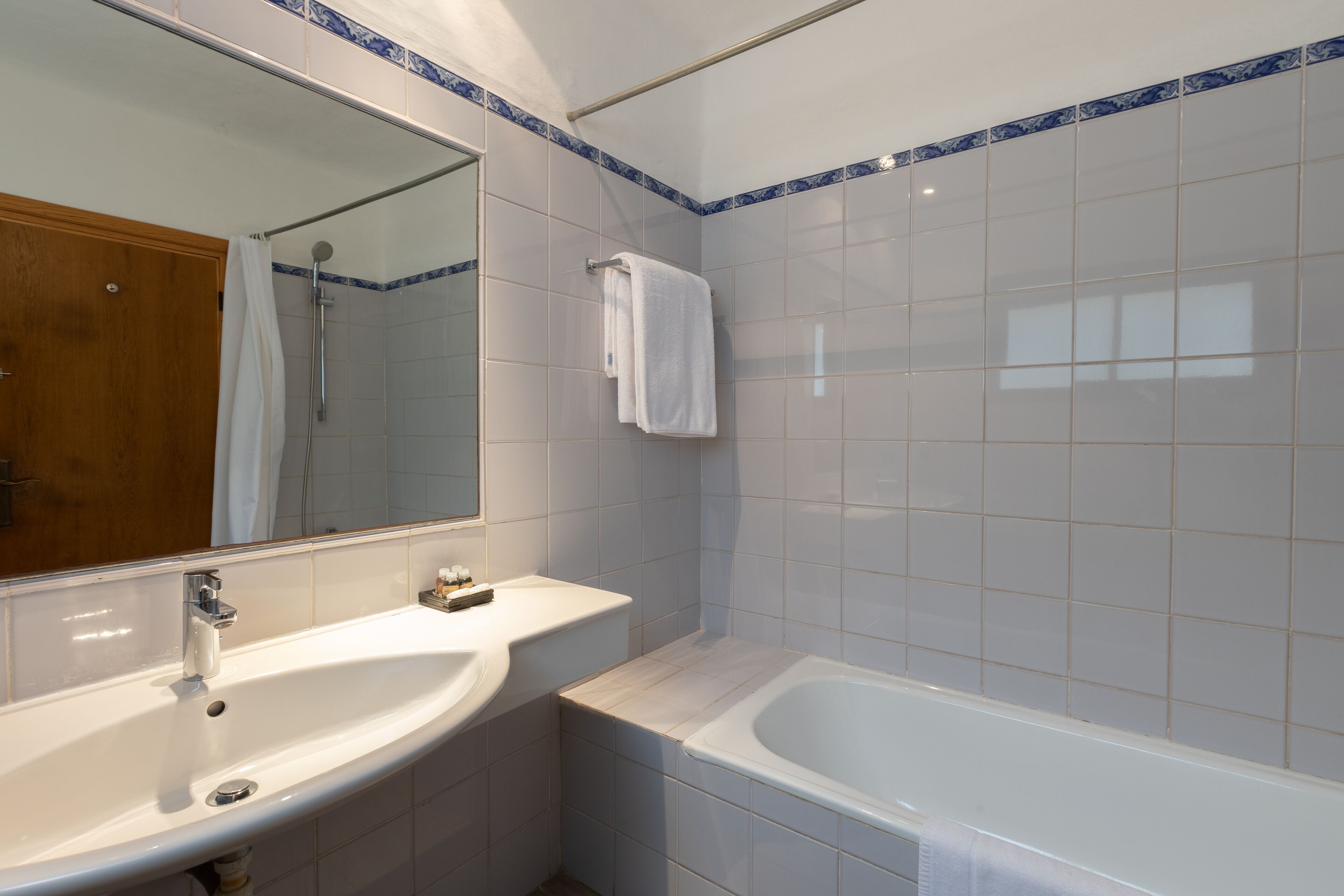 Un baño con lavamanos blanco, espejo, bañera y ducha.