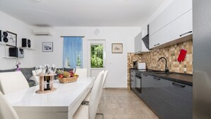 Une cuisine moderne avec des meubles blancs, un dosseret carrelé et un réfrigérateur en acier inoxydable.