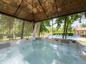 A hot tub with a bamboo roof, surrounded by trees and a pool in the background. - 4 bedroom villa with private swimming pool , with total privacy (Ružići)