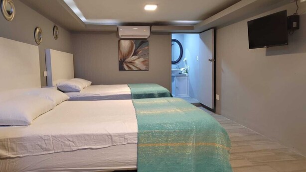 Une chambre d’hôtel avec deux lits, une salle de bain et un téléviseur fixé au mur.