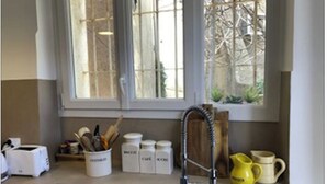 Una cuina amb un doble rentaplat i una finestra que dona a vegetació, a més d'estris i recipients de cuina diversos.