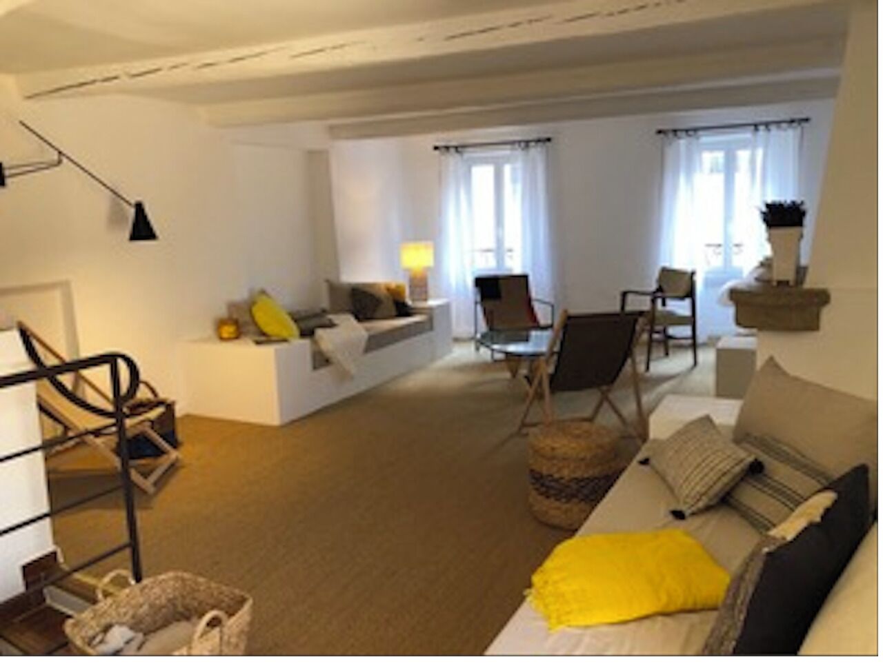 Uma sala de estar ampla com um sofá, poltronas, uma mesa de centro e um abajur.