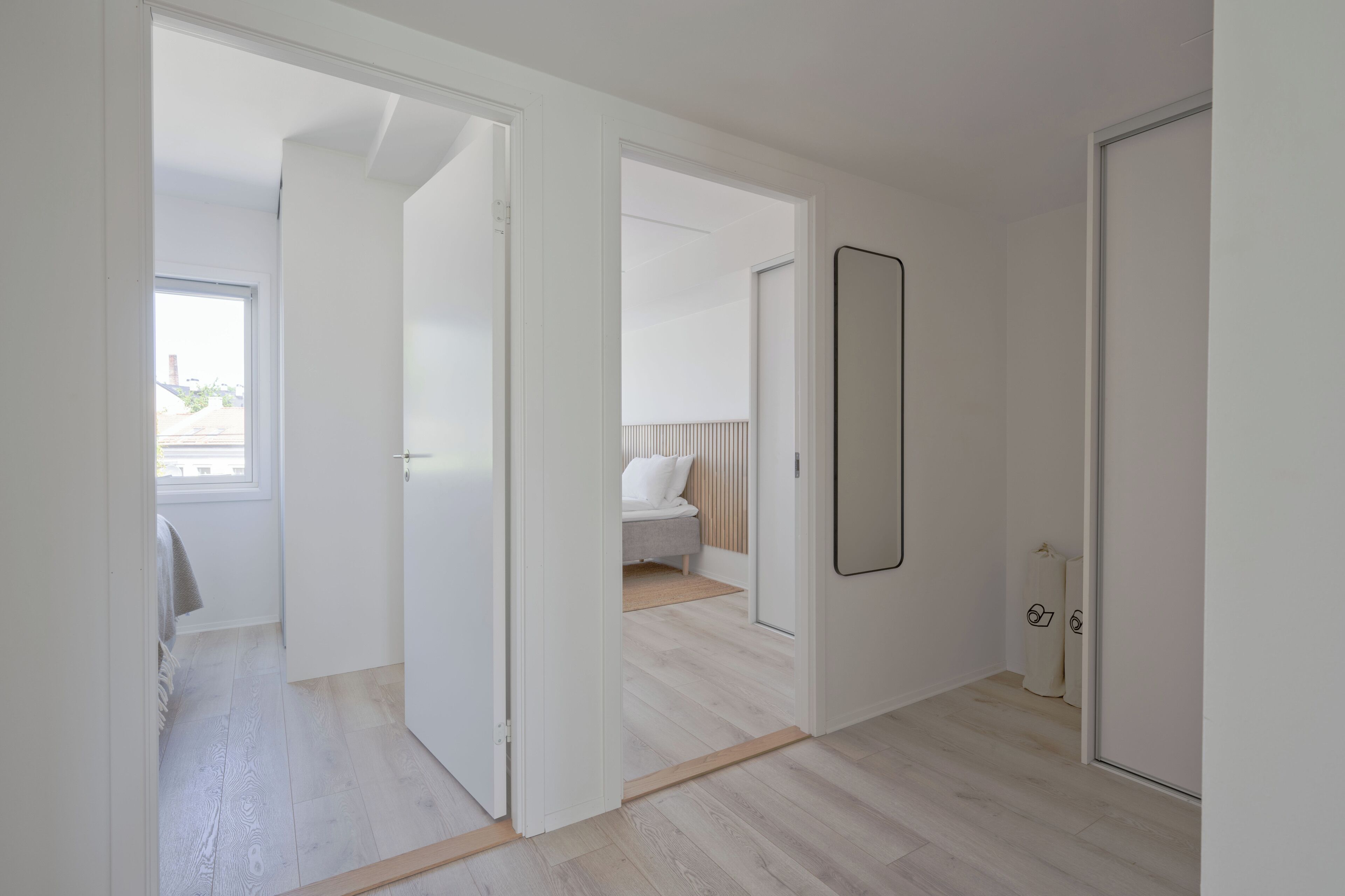 Un soggiorno moderno e open space con pavimento in legno, un grande specchio e vista su un balcone.