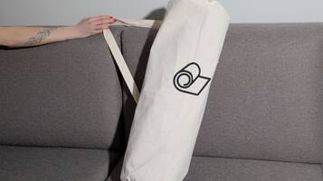 A grey sofa with a white bag featuring a black logo.