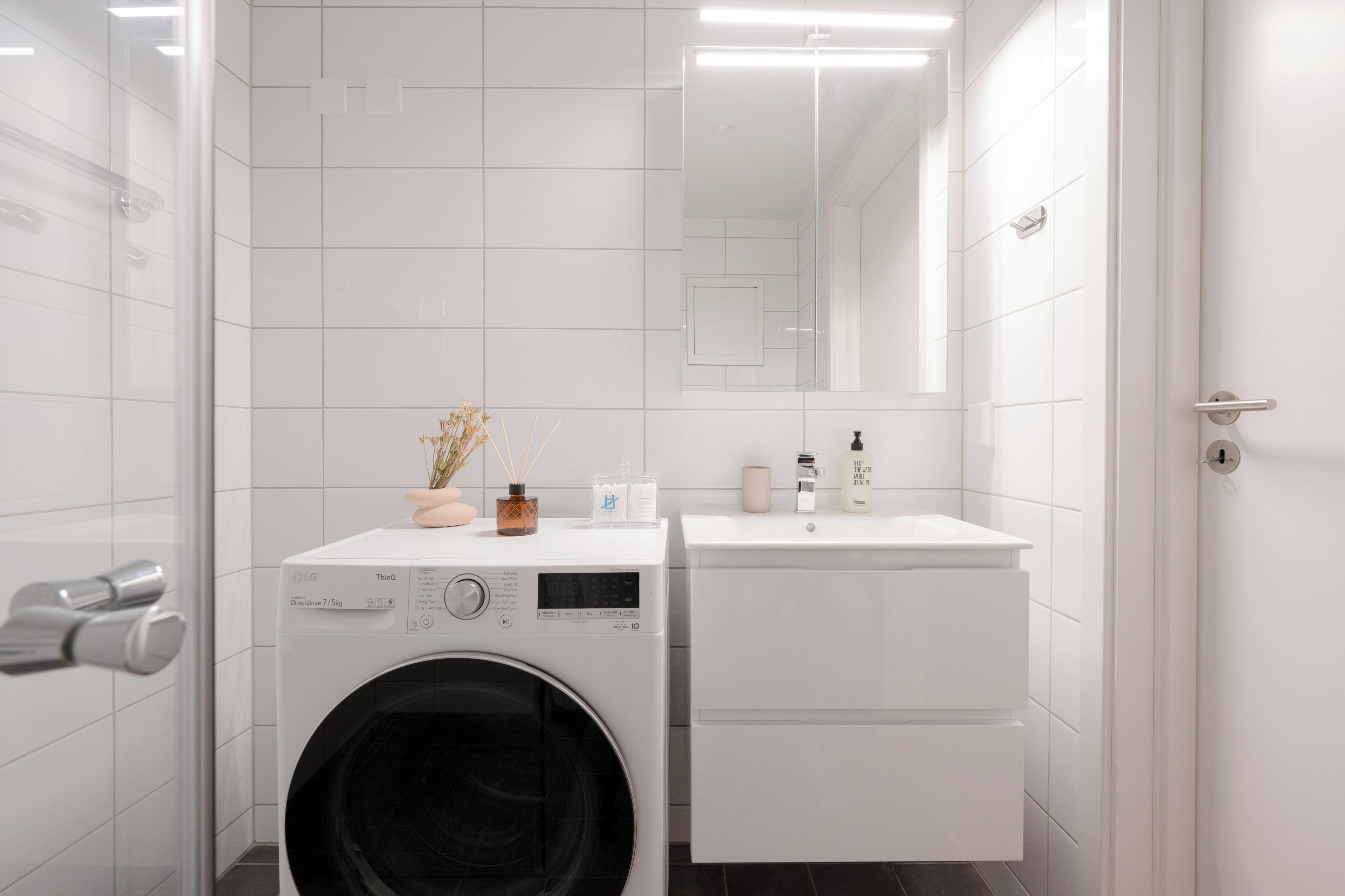 Un baño moderno con lavadora, lavamanos y espejo.