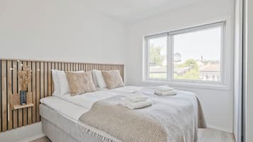 Een slaapkamer met een bed, een raam en een houten hoofdeinde.