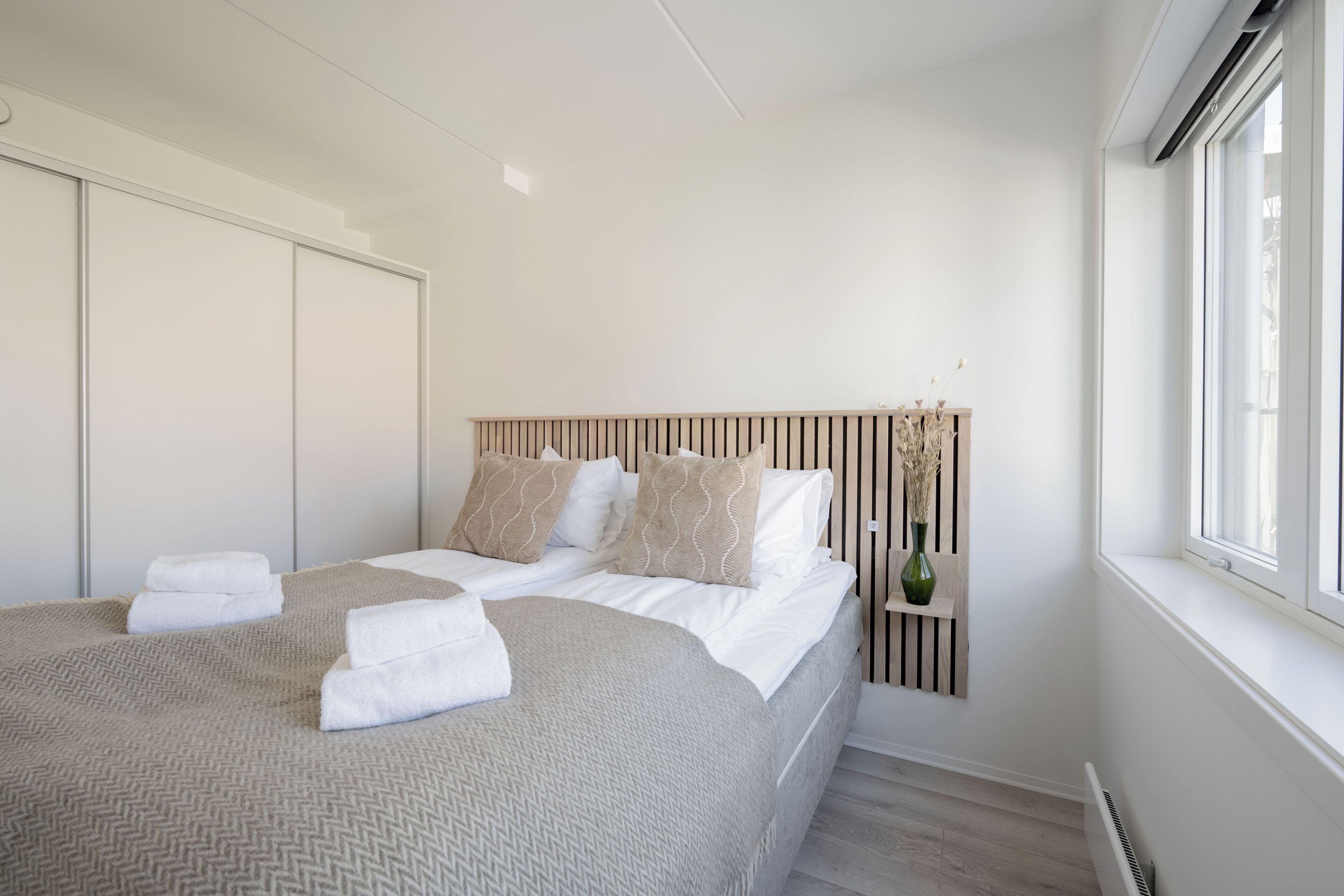Un dormitorio con cama, paredes blancas, una ventana y un radiador.