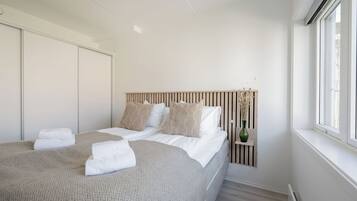 Un dormitorio con cama, paredes blancas, una ventana y un radiador.