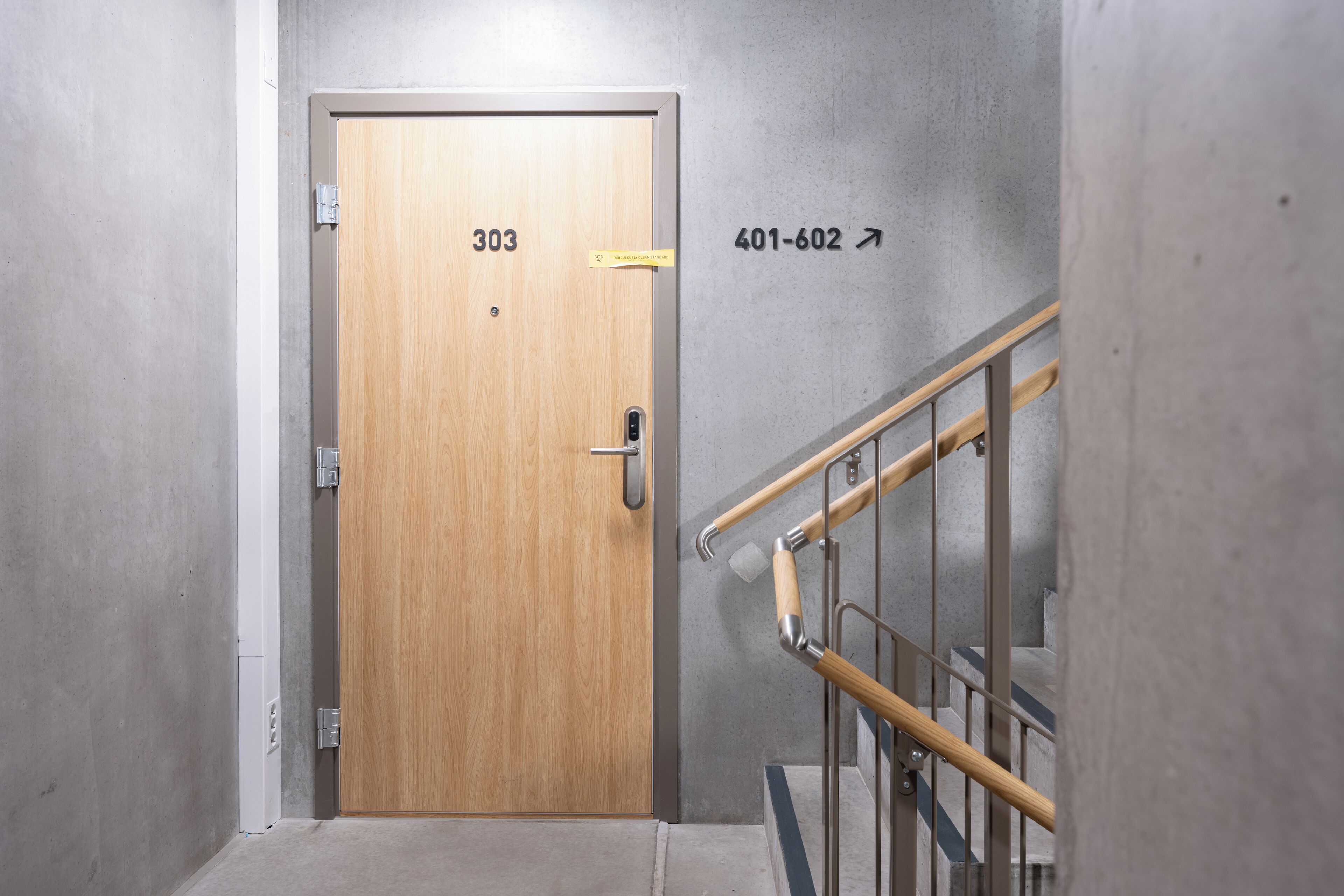 A wooden door with the number 303, a metal handrail, and a wall with the number 401-602.