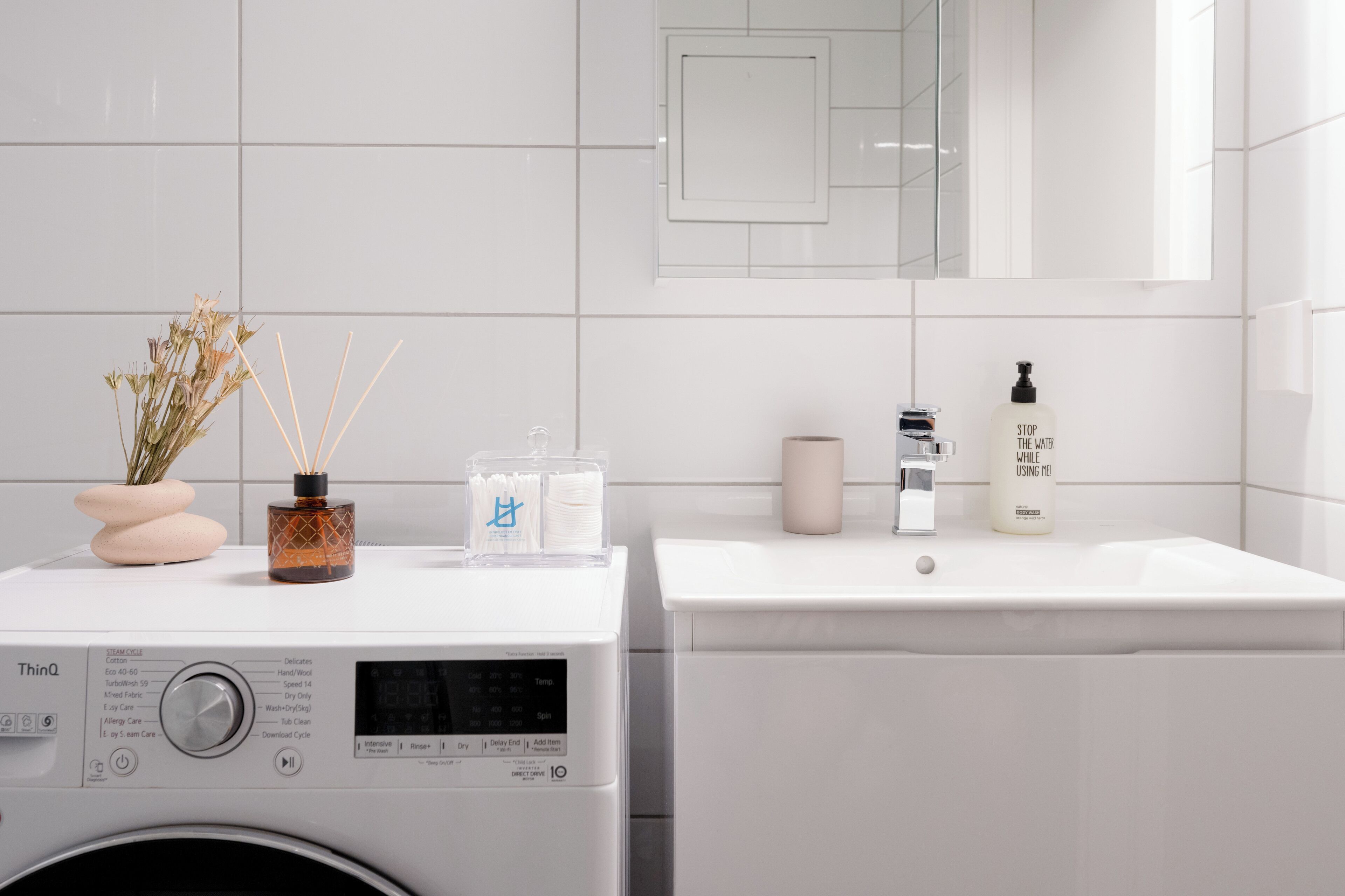 Une salle de bain moderne équipée d’un lave-linge, d’un lavabo et d’articles de toilette.