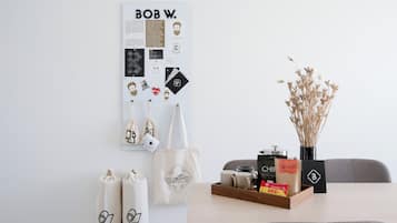 A wall with a poster, a table with a tray of items, and a vase with dried plants.