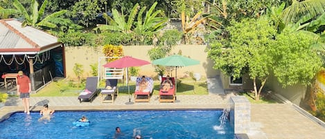 Een buitenzwembad, parasols voor strand/zwembad