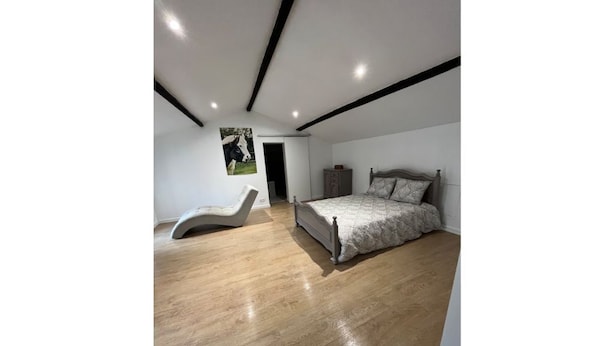 Ein Schlafzimmer mit einem Bett, einem Sessel und Holzboden.