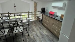Eine moderne Küche mit Essbereich, ausgestattet mit einem Oberlicht, Holzböden und einem Kühlschrank.