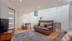 Un salon moderne avec un canapé en cuir marron, une table basse en bois, un téléviseur et un coin repas comprenant des chaises et une table.