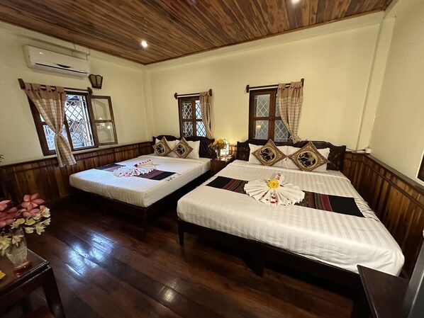 Quarto de hotel com duas camas, piso de madeira e teto de madeira.