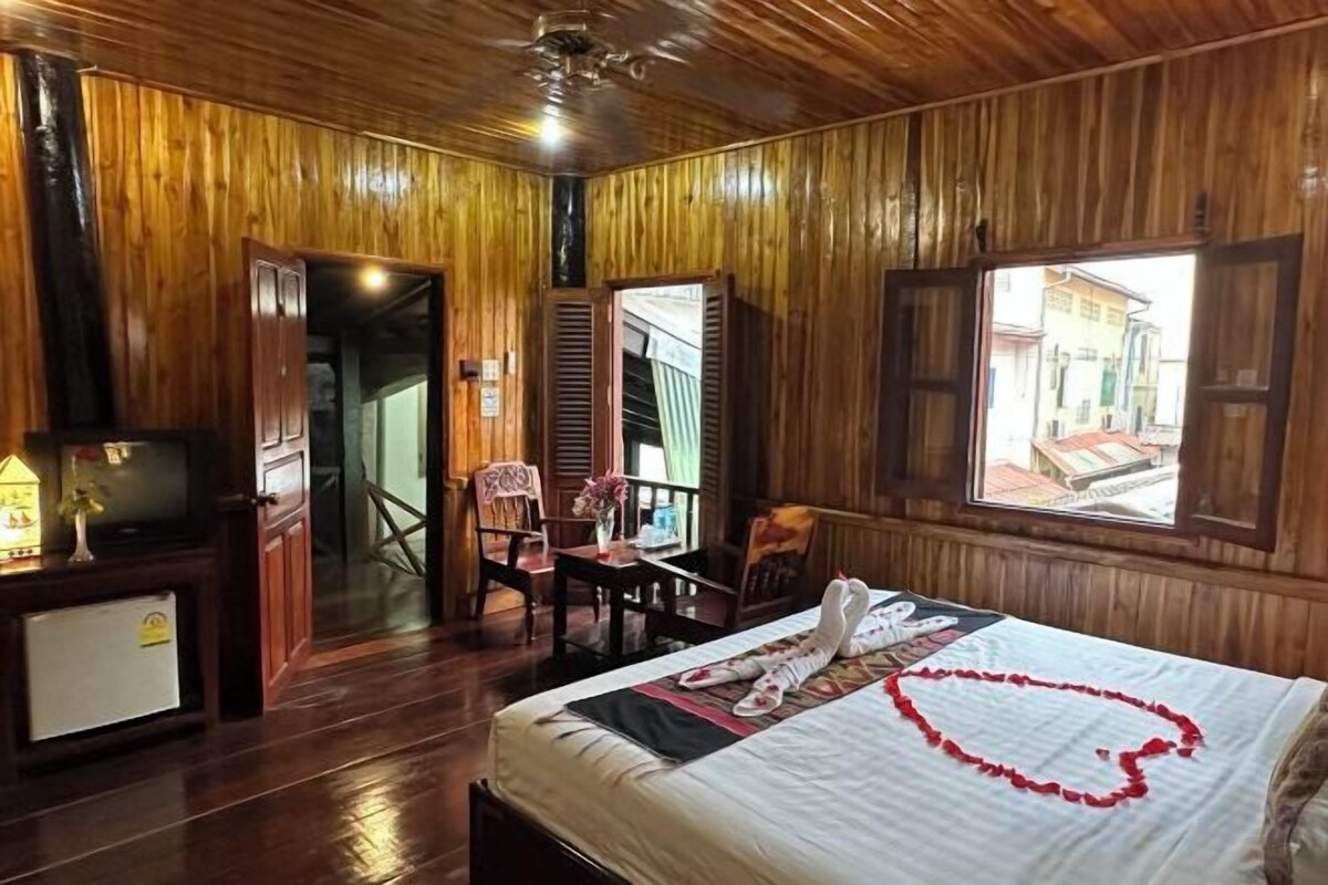 A wooden-paneled room with a bed, a desk, and a chair.
