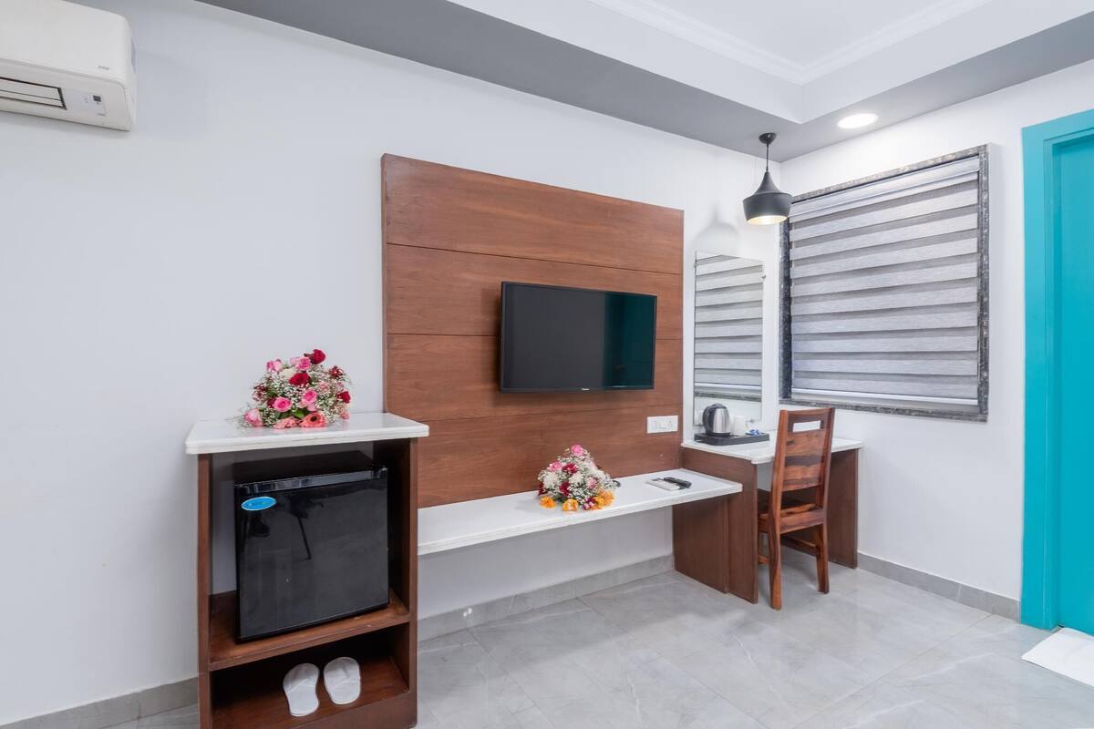 A modern bathroom with a wooden vanity, a built-in TV, a sink, and a shower area.