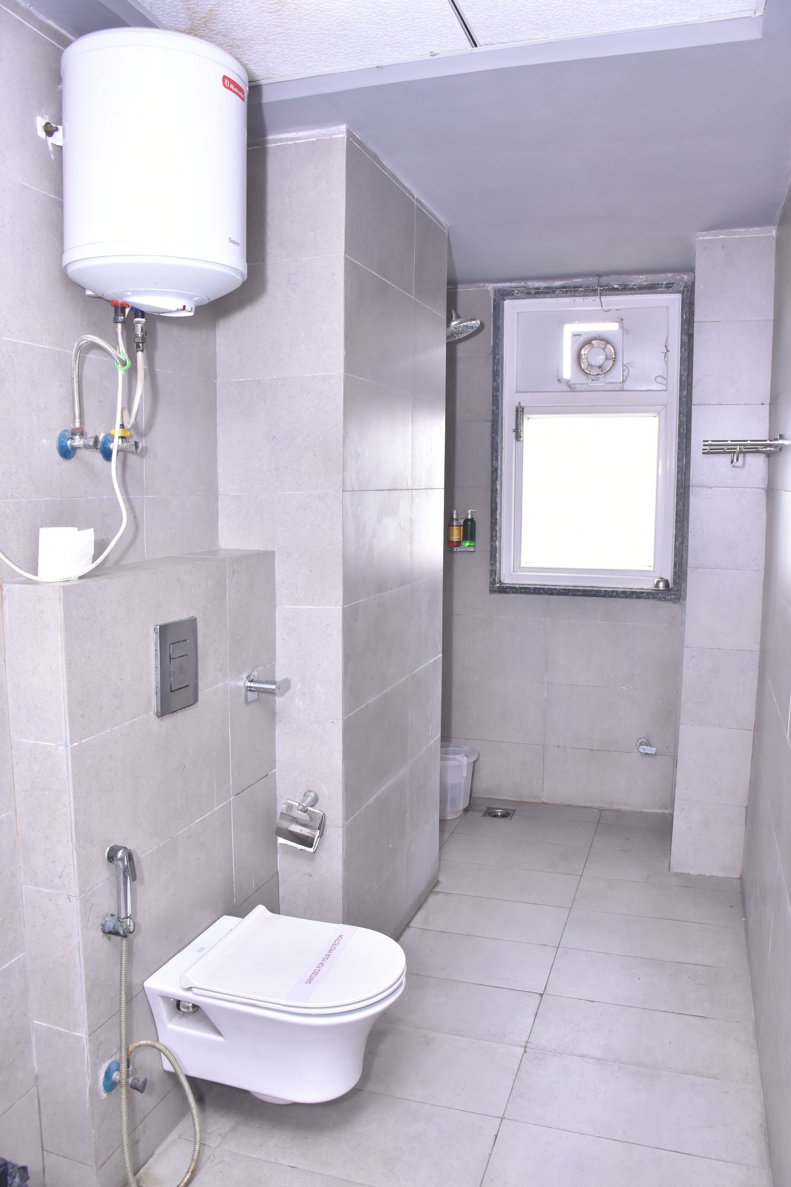 Un baño con inodoro, ducha y calentador de agua.