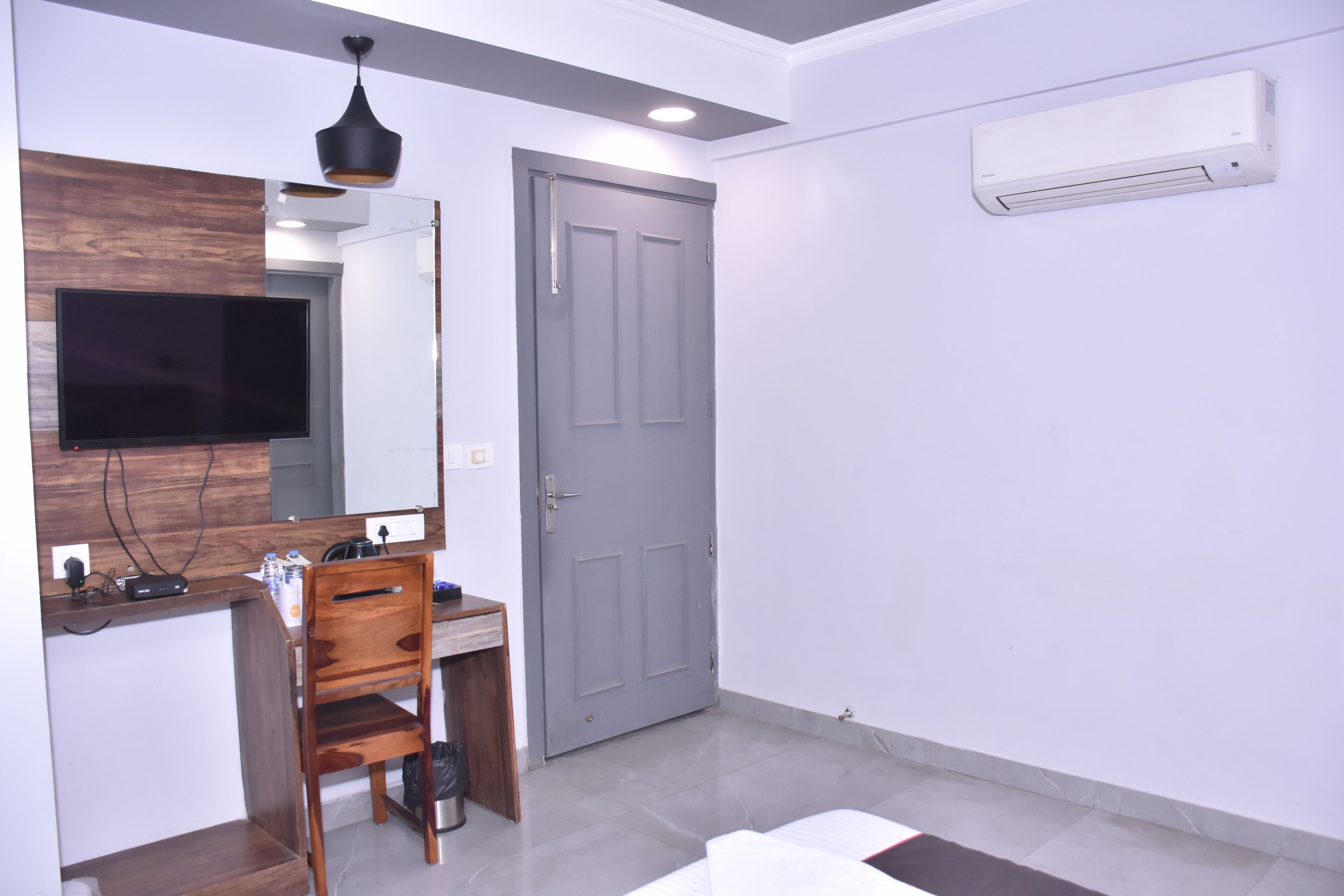 A modern bathroom with a wooden vanity, a mirror, a television, and an air conditioning unit.