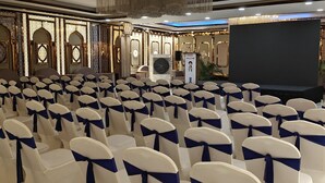 Een congreszaal met rijen stoelen, vastgebonden met blauwe linten, een podium en een spreekgestalte.