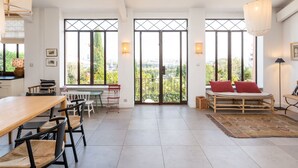 A spacious living area with a dining table, chairs, a sofa, and a large window offering a city view. - La vue - Charming house with a pool, garden and amazing view, (La Mulatière)