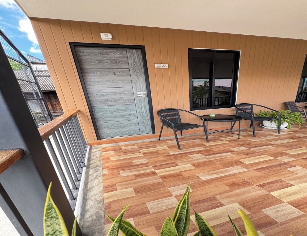 A balcony with a wooden floor, a door, and a window.