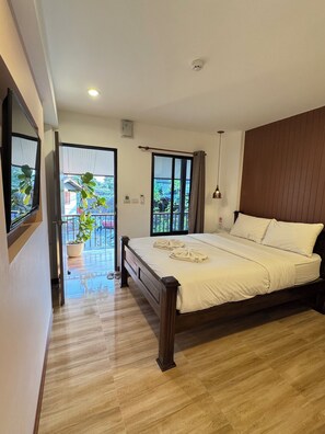 Een slaapkamer met een houten bed, een balkon met een bloempot en uitzicht op groen.