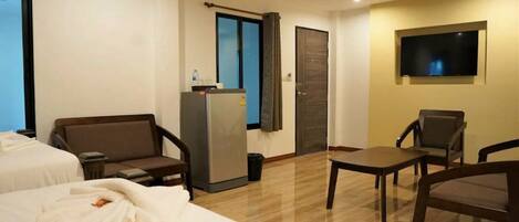 A hotel room with two beds, a desk, a chair, a TV, and a minibar.