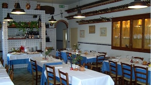 A restaurant with multiple tables set for dining, featuring a tiled backsplash, hanging pendant lights, and wooden cabinets. - Residence Casprini da Omero (Greve in Chianti)