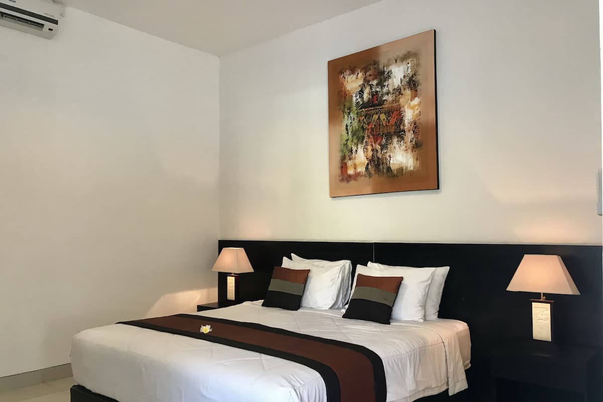 A modern hotel room with a large bed, two bedside tables, and a wall-mounted abstract painting.