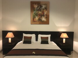 Ein Hotelzimmer mit einem großen Bett, zwei Nachttischen, zwei Lampen und einem Bild an der Wand.