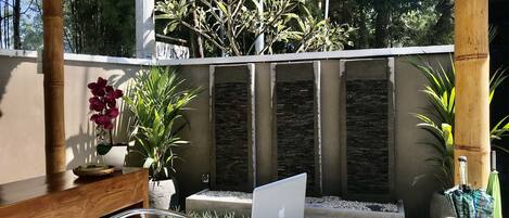 A patio area with a round marble table, a laptop, and a wooden table with chairs.