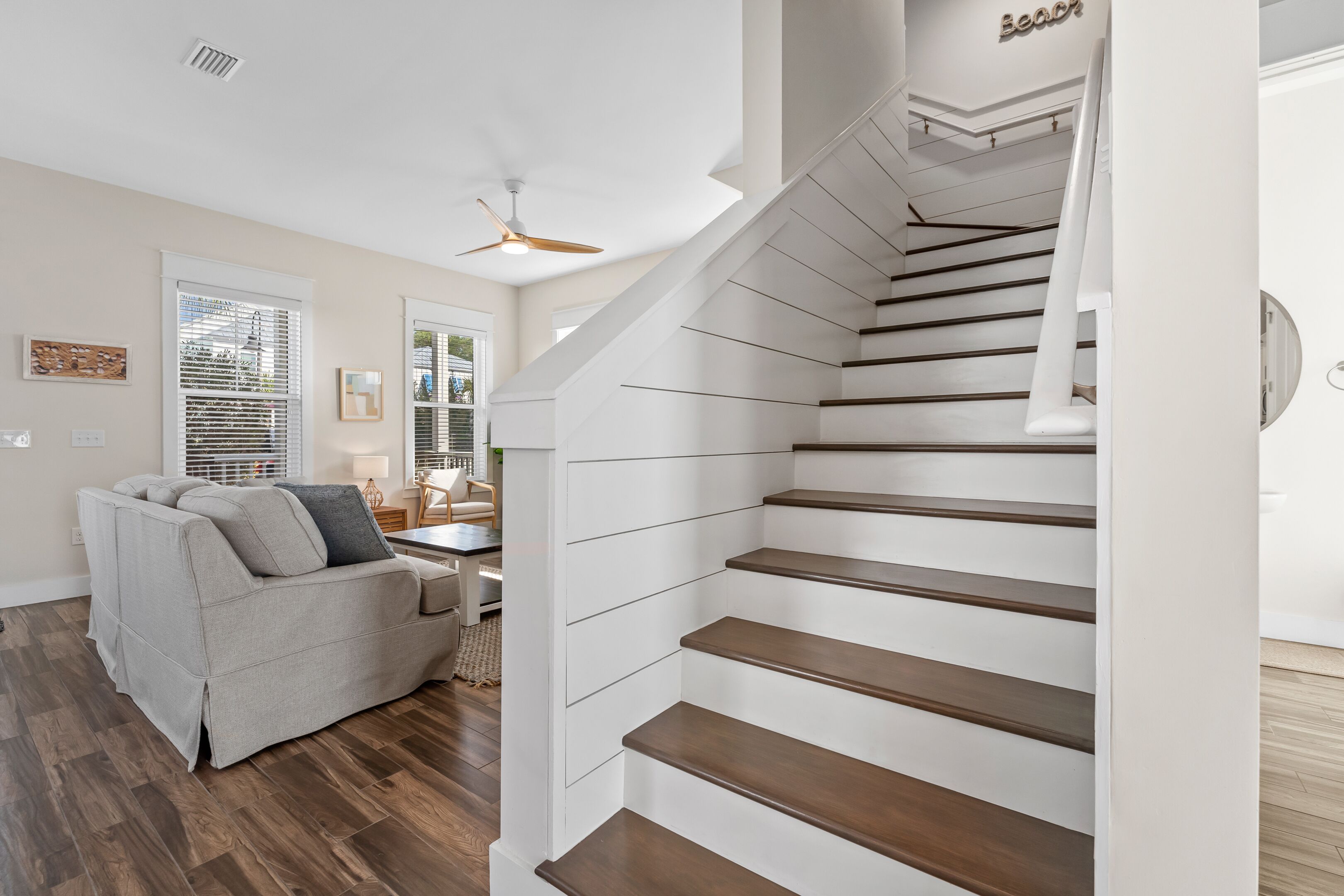 A modern interior with a staircase, a sofa, and a ceiling fan.