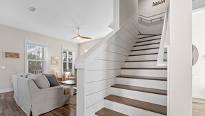 Un interior moderno con una escalera, un sofá y un ventilador de techo.