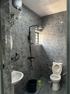 Ein Badezimmer mit Dusche, Waschbecken, Toilette und einem kleinen Fenster.
