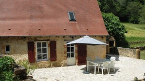A stone house with a red roof, a patio with a table and chairs, and a small window. - time for a break-The little house in the center of the village with a view of the castle (Berbiguieres)