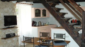 A cozy kitchen with a dining table, chairs, a TV, and a staircase. - time for a break-The little house in the center of the village with a view of the castle (Berbiguieres)