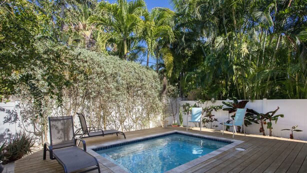 A wooden deck with a swimming pool, lounge chairs, and tropical plants. - Sunshine Escape- 3 bedroom 3 bath w/ parking for 2, private pool, balcony (Key West)