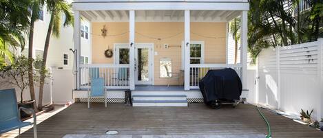 A two-story house with a wooden deck, a swimming pool, and a covered grill area.