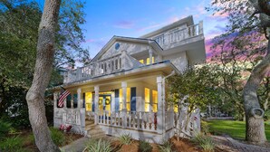 A two-story house with a porch, surrounded by trees and a well-maintained lawn.