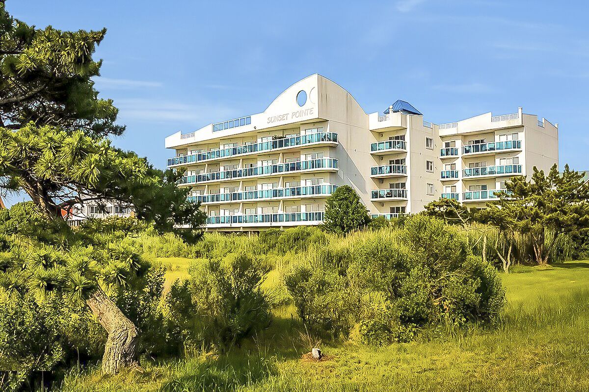 A multi-story hotel with balconies, surrounded by lush greenery.
