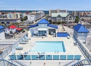 A hotel with a rooftop pool, multiple buildings in the background, and a clear view of the ocean.