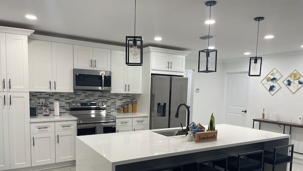 A modern kitchen with white cabinets, stainless steel appliances, and a central island with bar stools. - Pool House 3/2: Grill, Mural and Ping Pong Table (Sunrise)