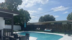 A backyard with a swimming pool, patio furniture, and a wooden fence. - Pool House 3/2: Grill, Mural and Ping Pong Table (Sunrise)