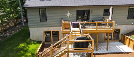 Une maison à deux étages avec une terrasse, un panneau indiquant les points cardinaux et un espace patio.