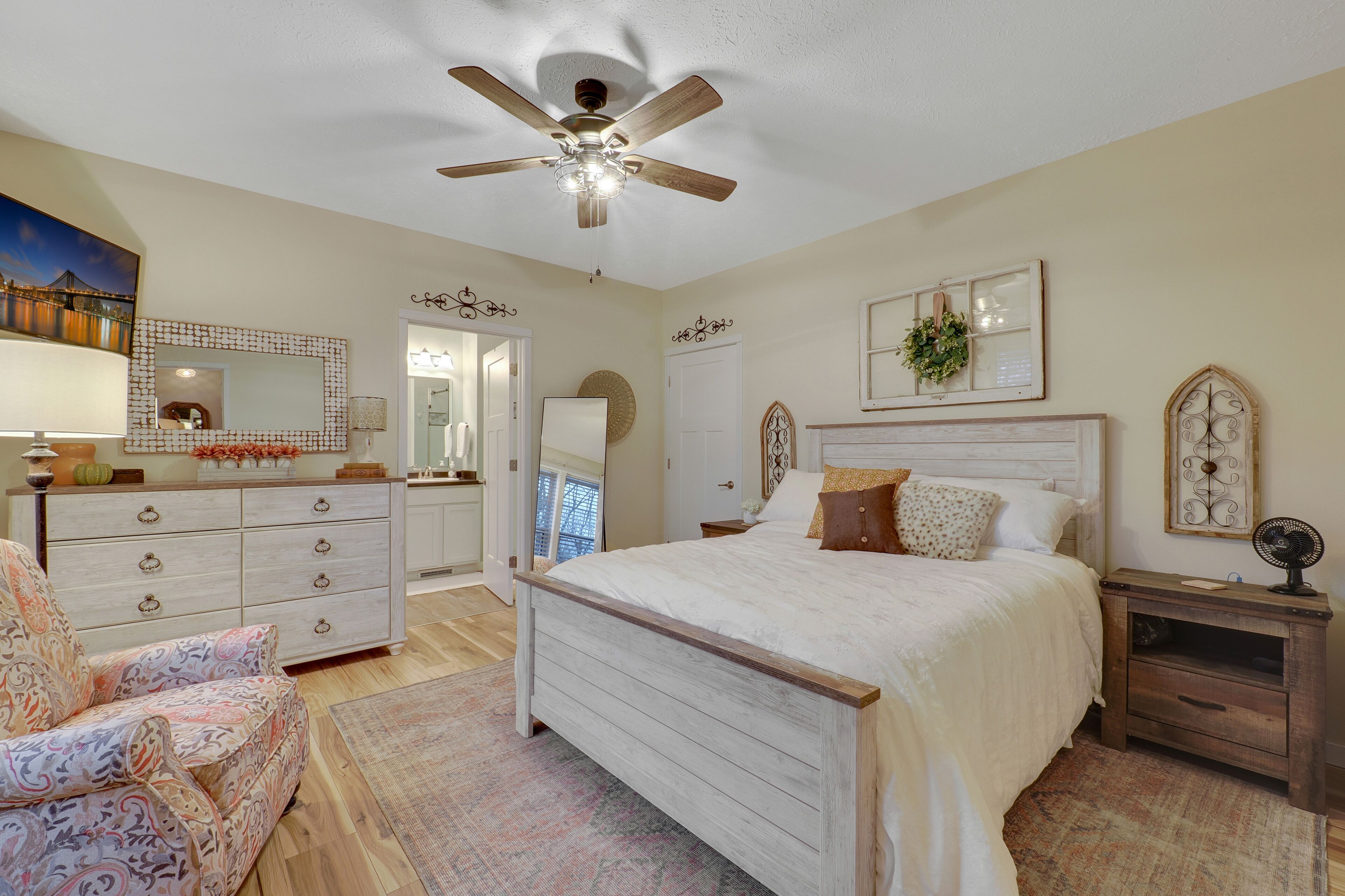 Une chambre à coucher avec un lit, une commode, une chaise et un ventilateur de plafond.