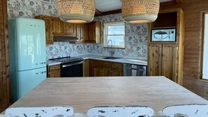Eine Küche mit Holzausstattung, einem türkisfarbenen Kühlschrank und einem großen Holztisch.